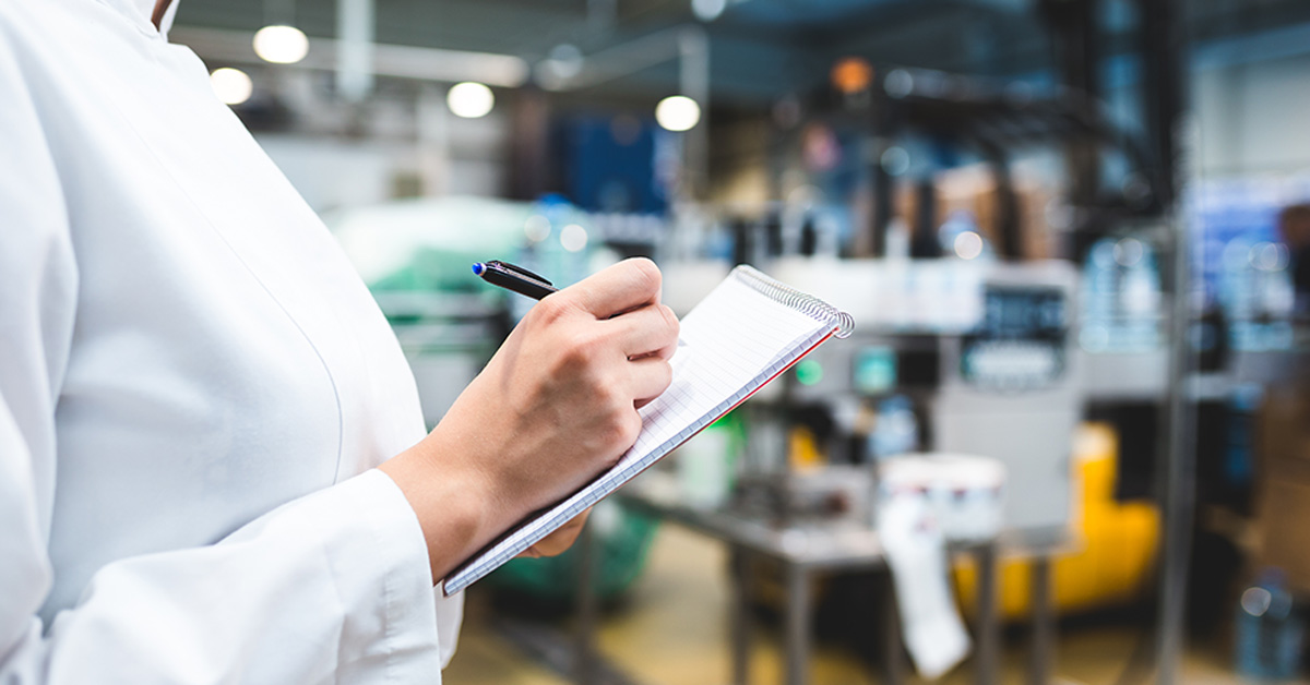 Woman In Lab Coat Writing In Notepad