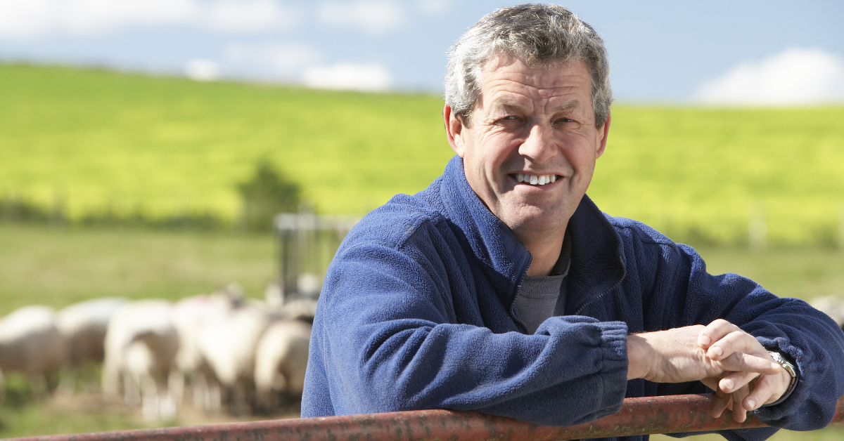 alt="farmer leaning on fence in front of his herd"