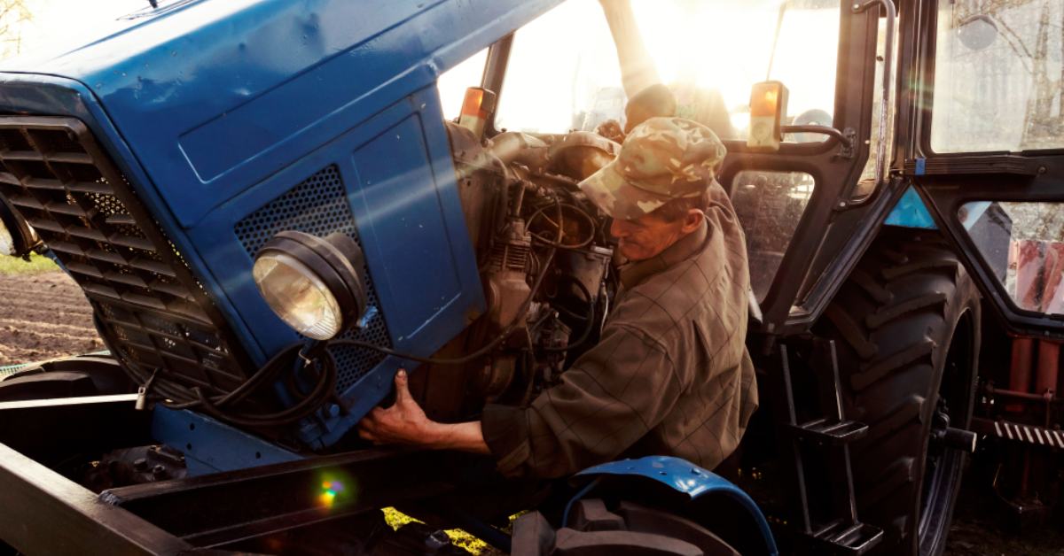 alt="Farmer repairing tractor"